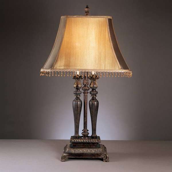 Классический настольный светильник с текстильным абажуром, украшенным бахромой и металлической ножкой с декоративными элементами